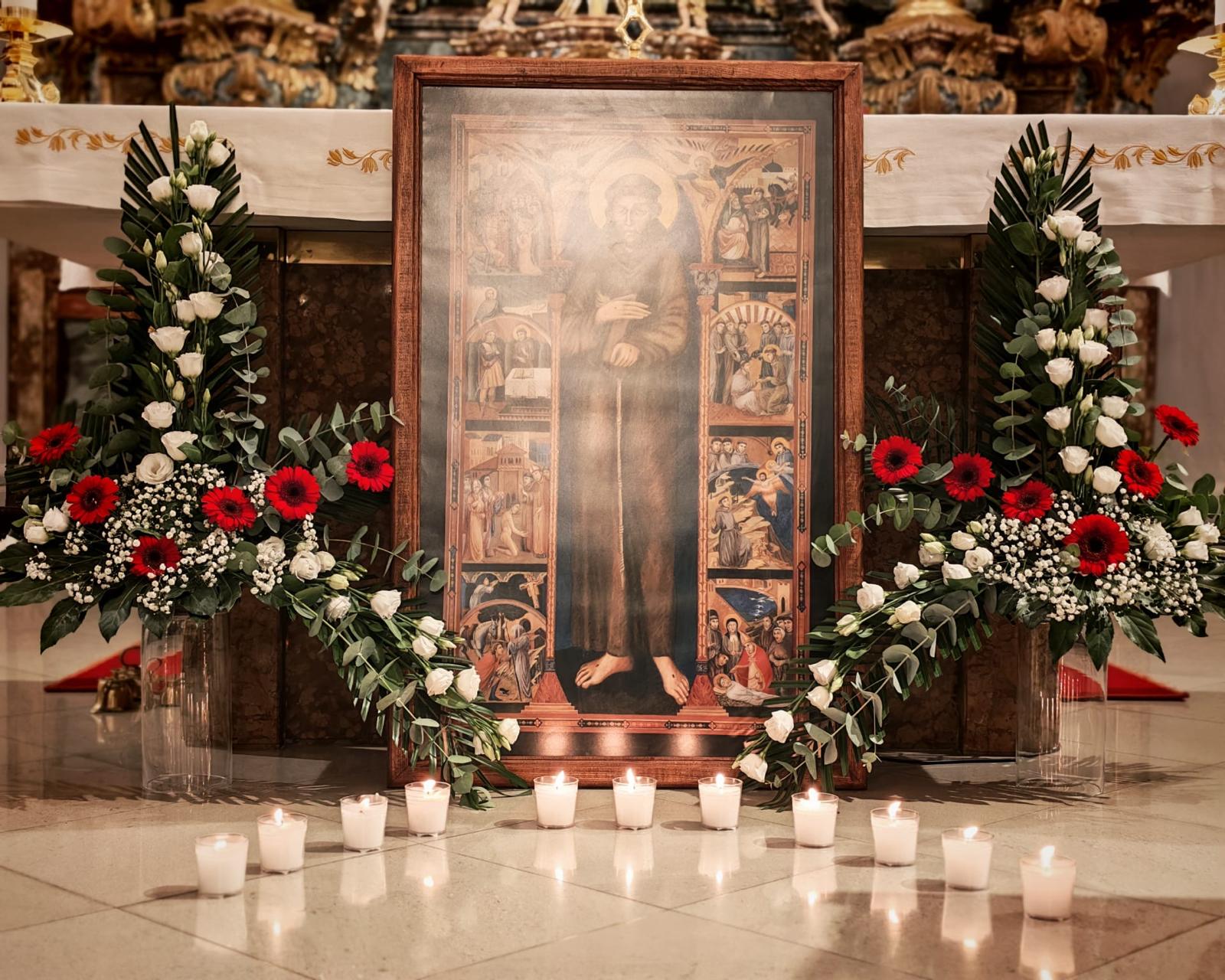 Slika sv. Franje uz svijeće i cvijeće ispred oltara